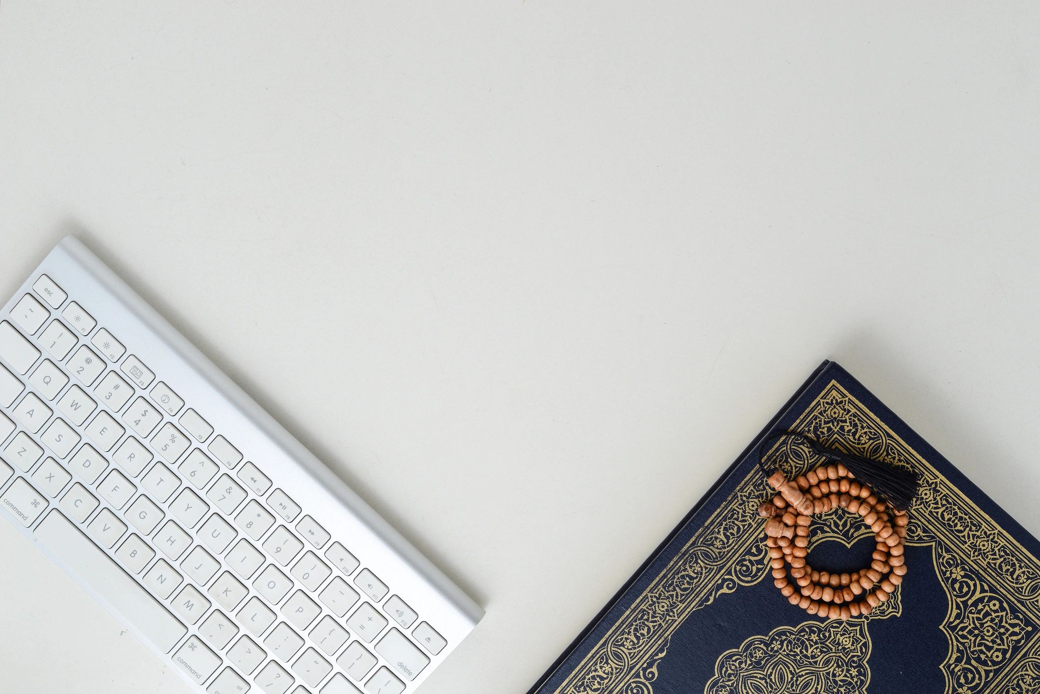 Desk with Arabic book, keyboard and prayer beads representing Arabic-language context